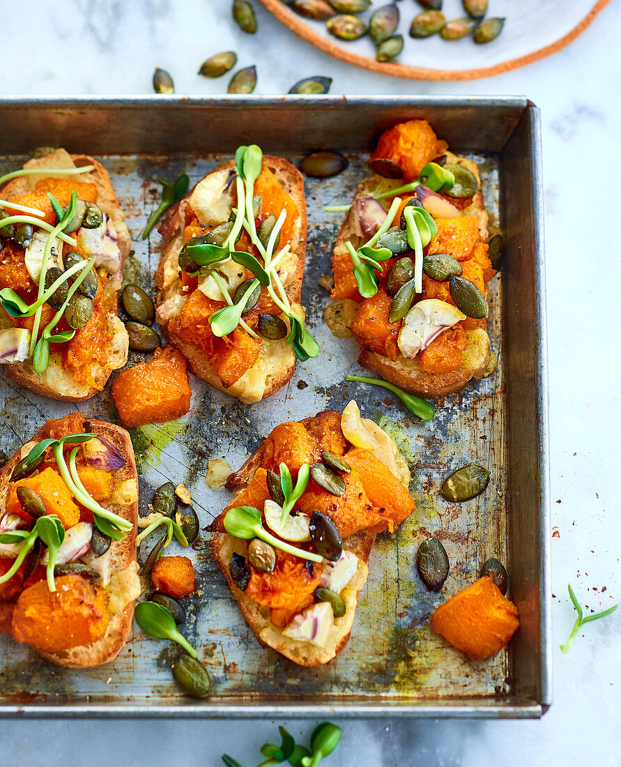 Crostini with pumpkin, seeds and sprouts on a tray (vegetarian)