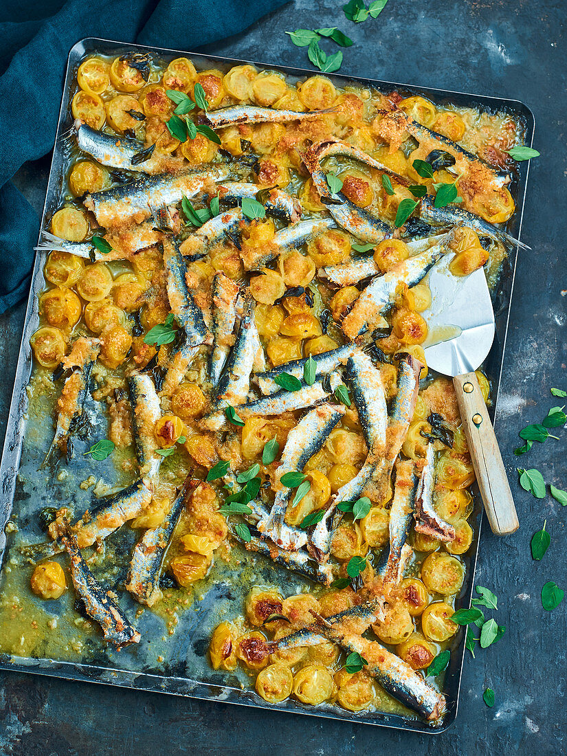 Boquerones con tomatoes (anchovies and yellow cherry tomatoes on a baking sheet)