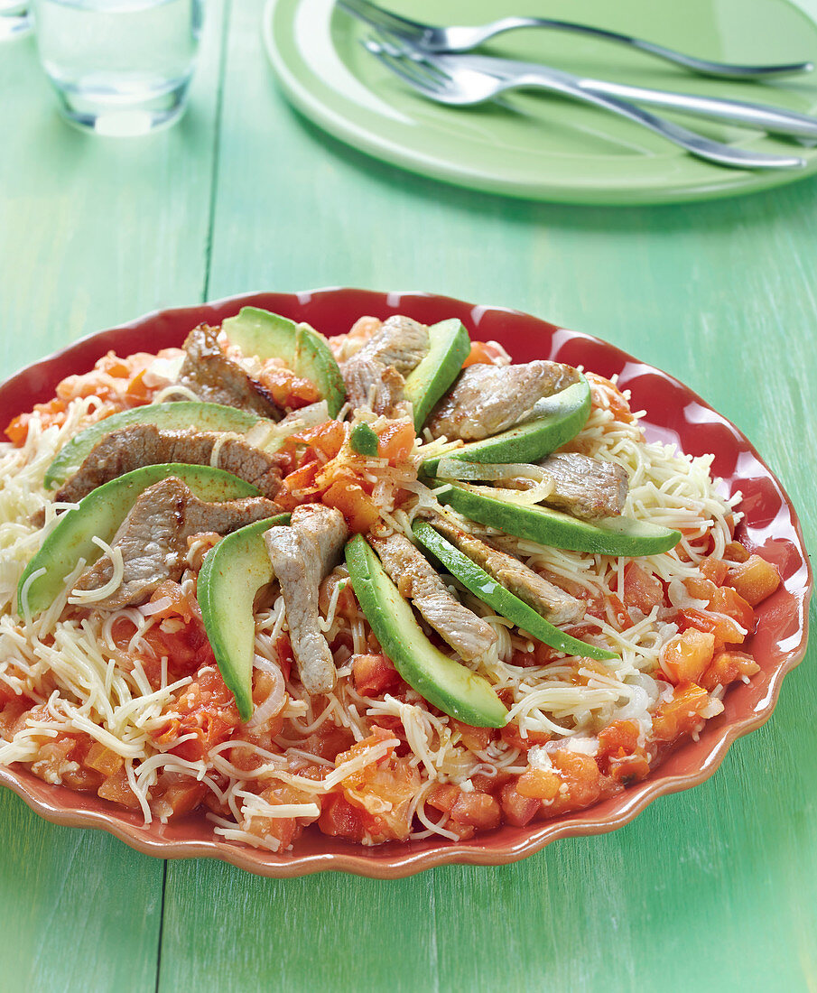 Angel hair pasta with veal,tomatoes and onions and sliced avocado