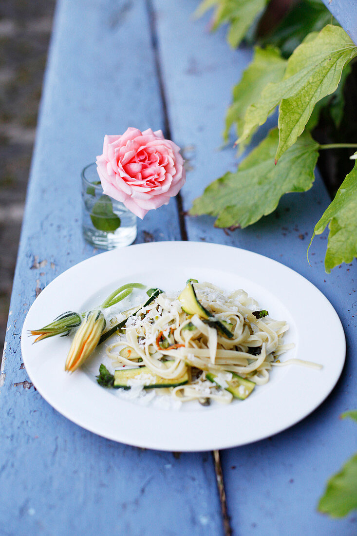 Tagliatelles with flowers and thinly sliced courgettes outdoors