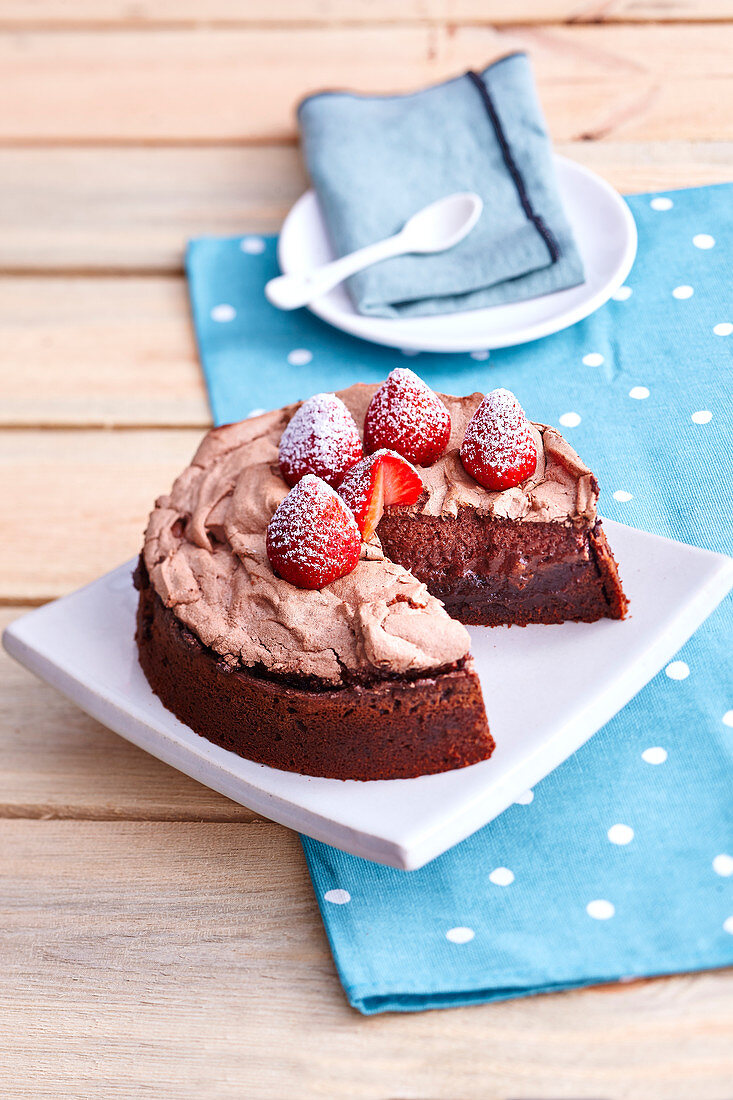 Schokoladenkuchen mit Baiserhaube und frischen Erdbeeren mit Puderzucker