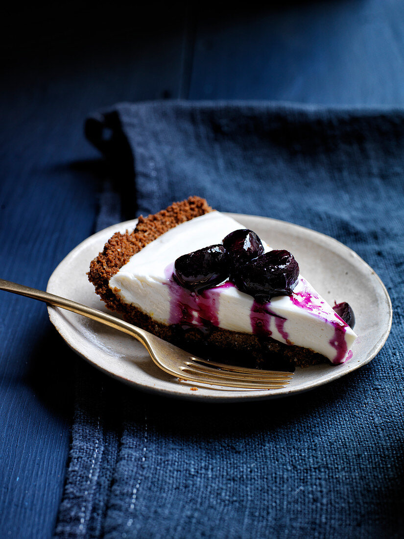Slice of yogurt pie with grape compote and black pepper and ginger crust