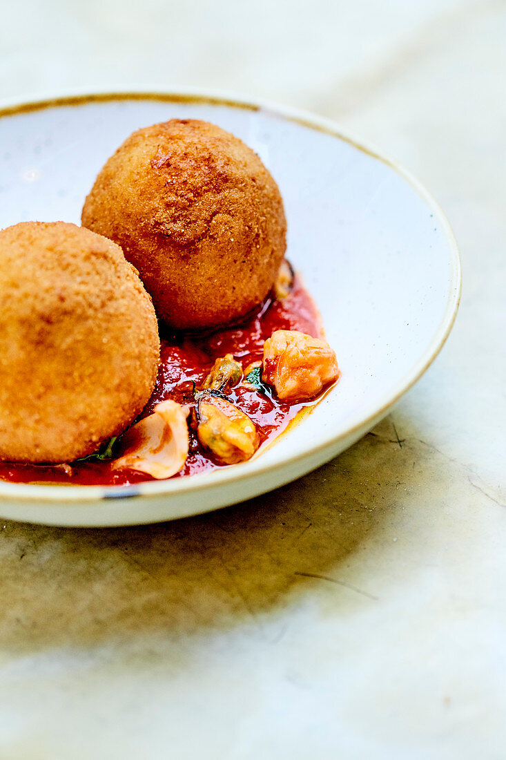 Arancini And Pan-Fried Sea Food In Tomato Sauce With Parsley