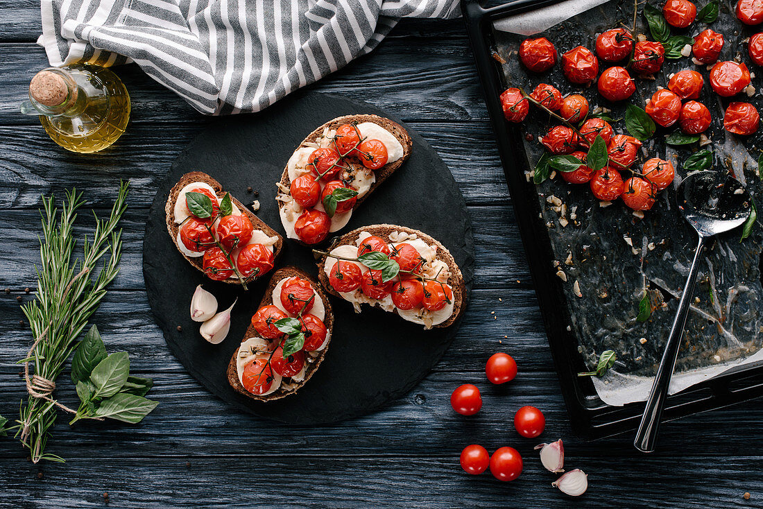 Delicious sandwiches with mozzarella and baked tomatoes on dark slate board