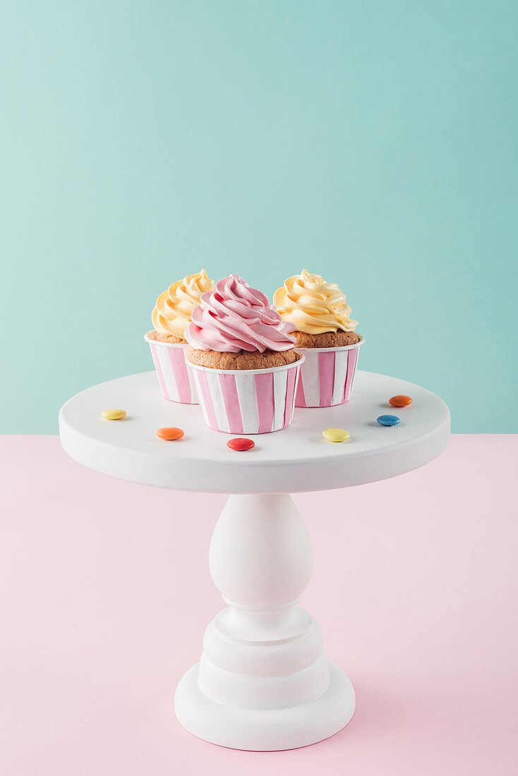 cupcakes with buttercream and candies on cake stand