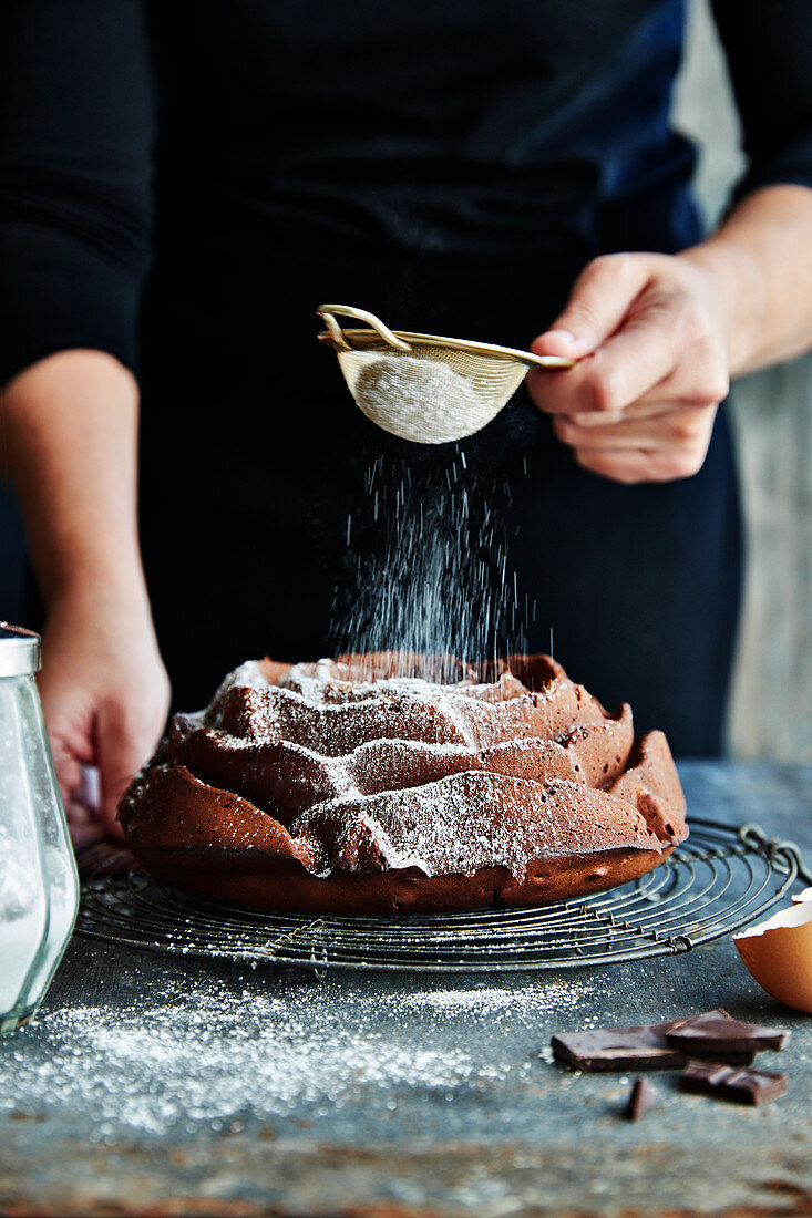 Schokoladenkuchen in Rosenform wird mit Puderzucker bestreut