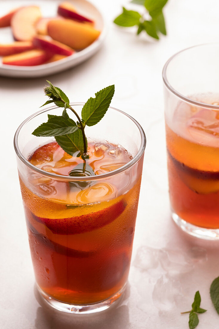 Iced black tea with slices of nectarines and mint.
