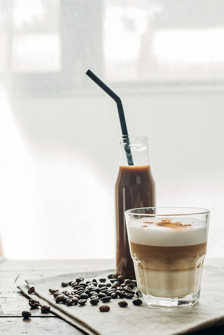 Kaffeegetränk in Flasche und ein Glas Cappuccino