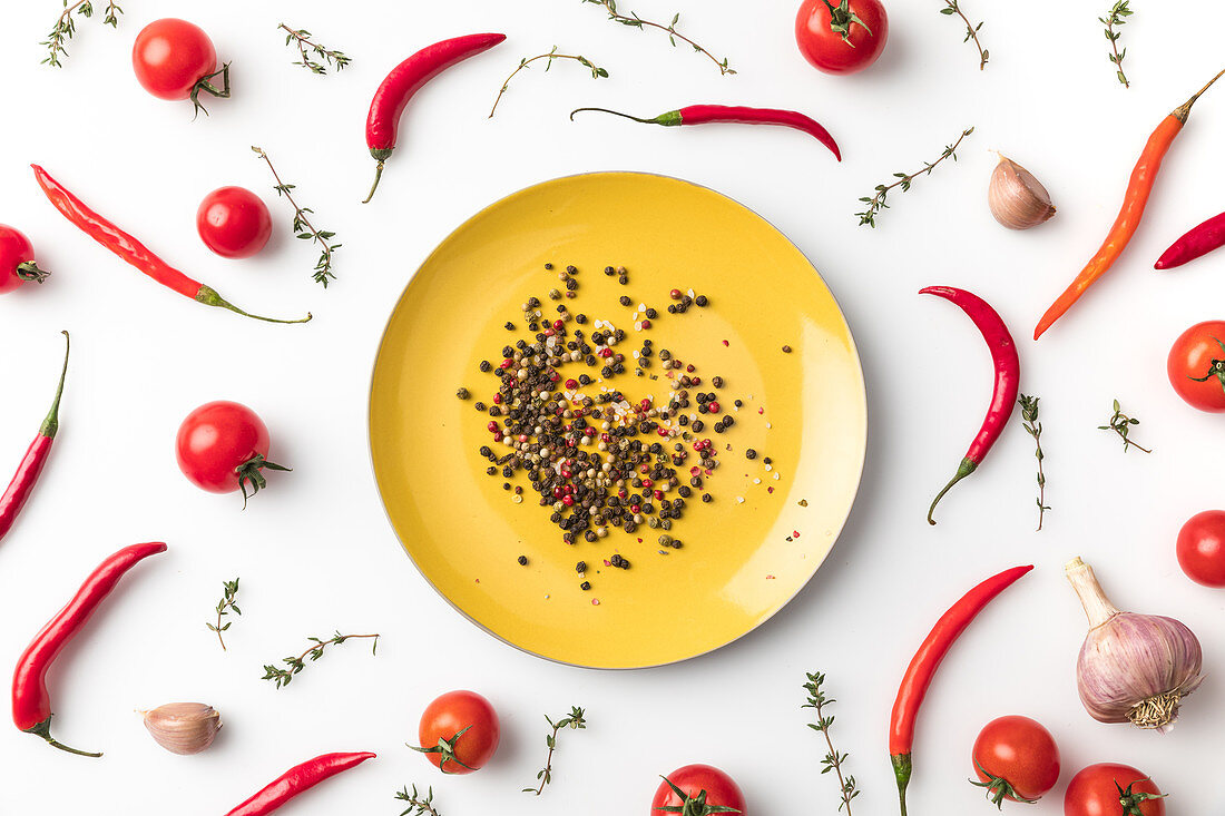 Peppercorns on a plate surrounded by chillies and tomatoes