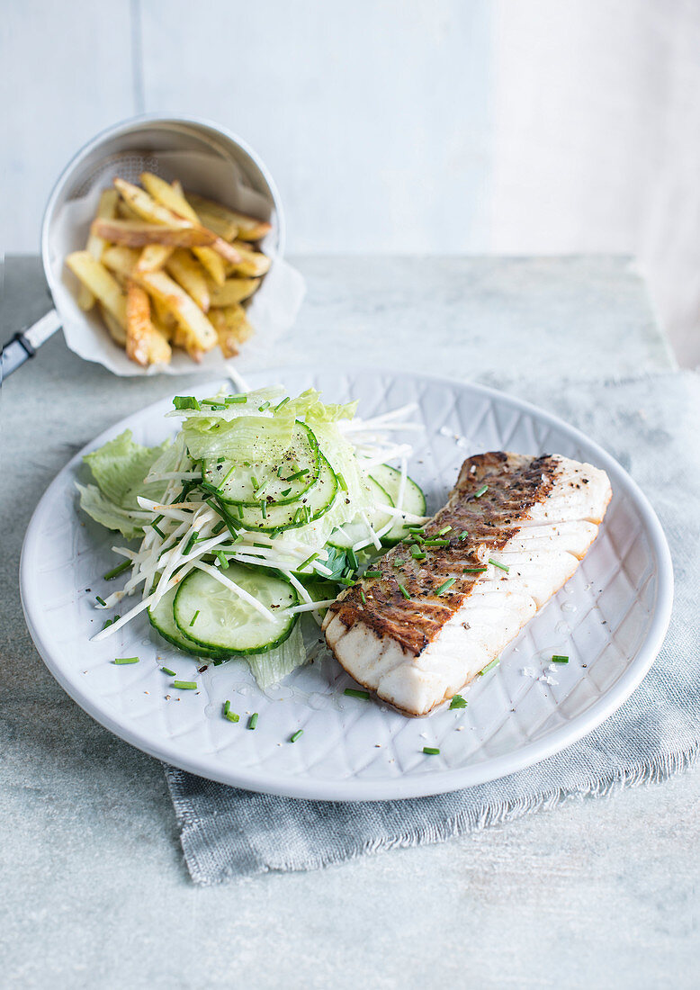 White fish fillet with cucumber salad and french fries