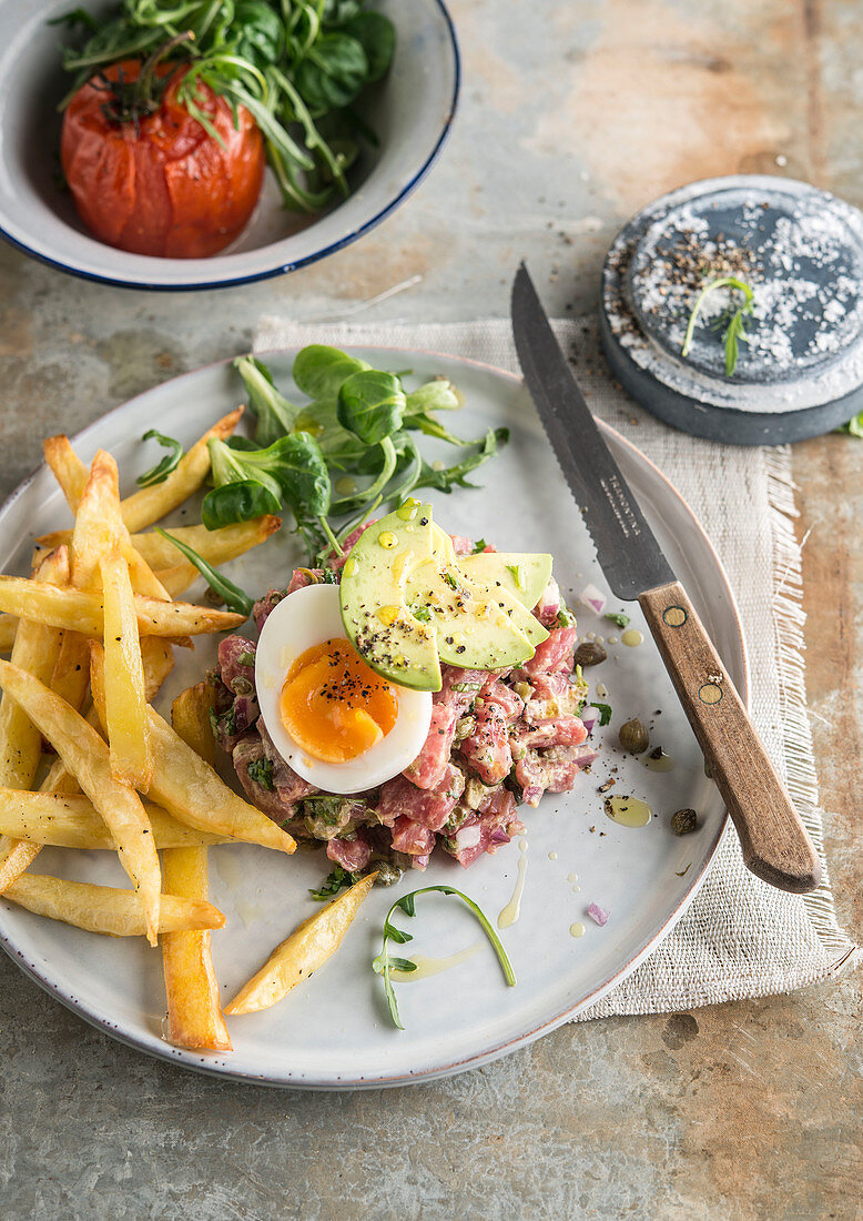 Steak tartare with boiled egg, avocado and chips
