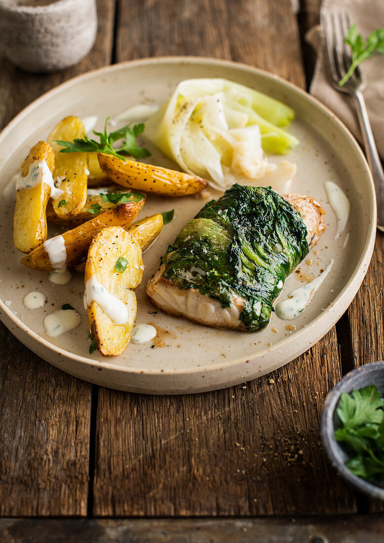 Fish fillet wrapped in spinach with fried potatoes and leeks