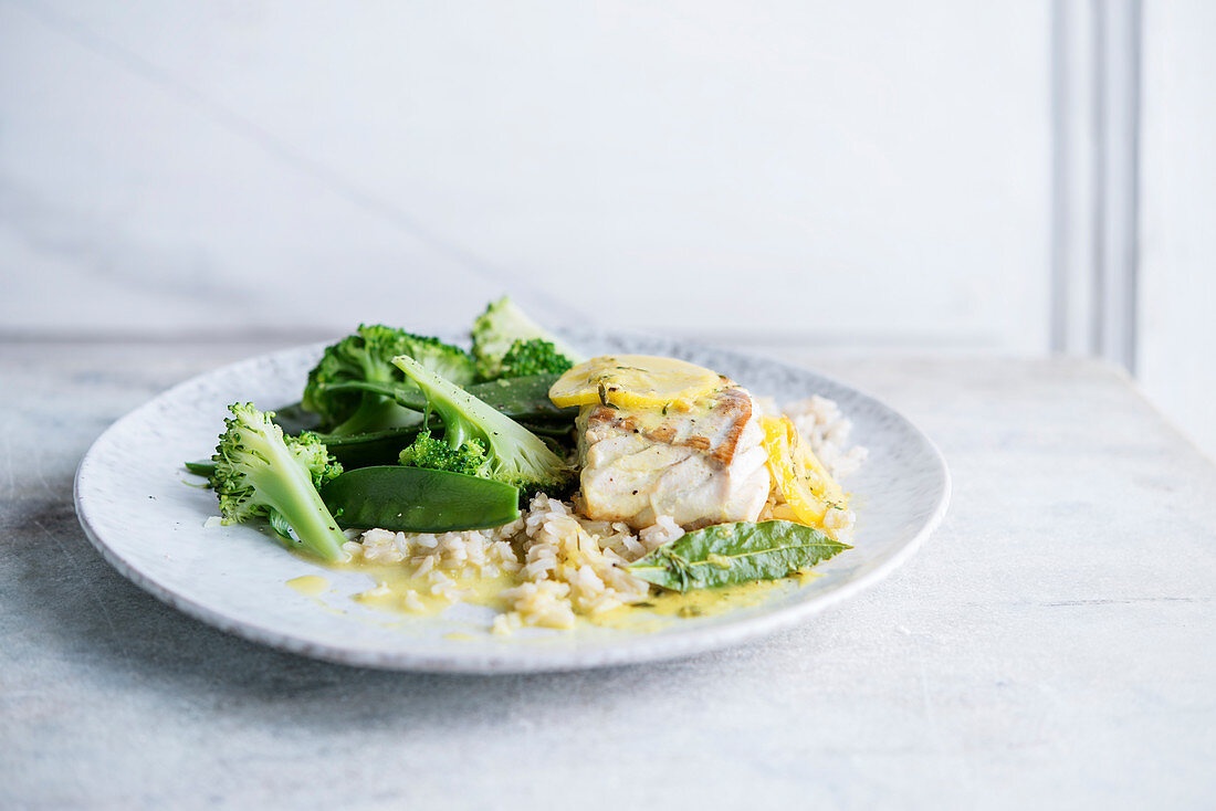 Fish fillet with lemon sauce served with broccoli and sugar snap peas