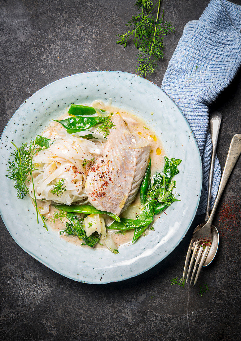 Fish with ribbon noodles and green vegetables in coconut milk