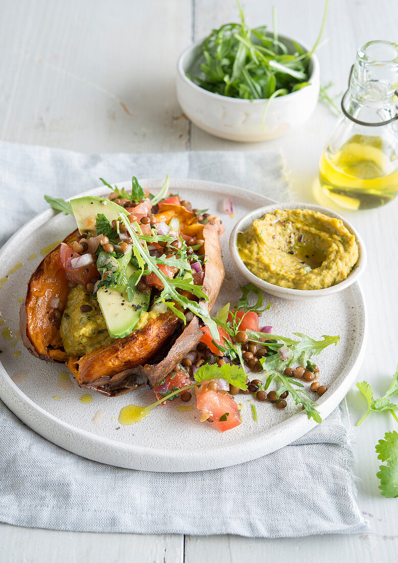 Sweet potato stuffed with hummus, tomatoes, avocado and lentils