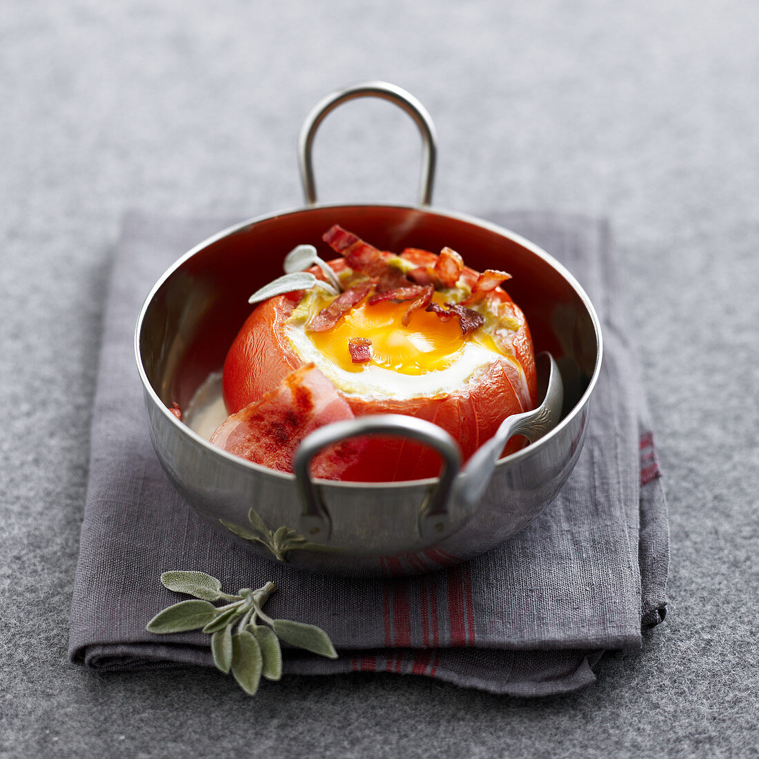 Baked tomato garnished with oeuf cocotte and bacon cubes