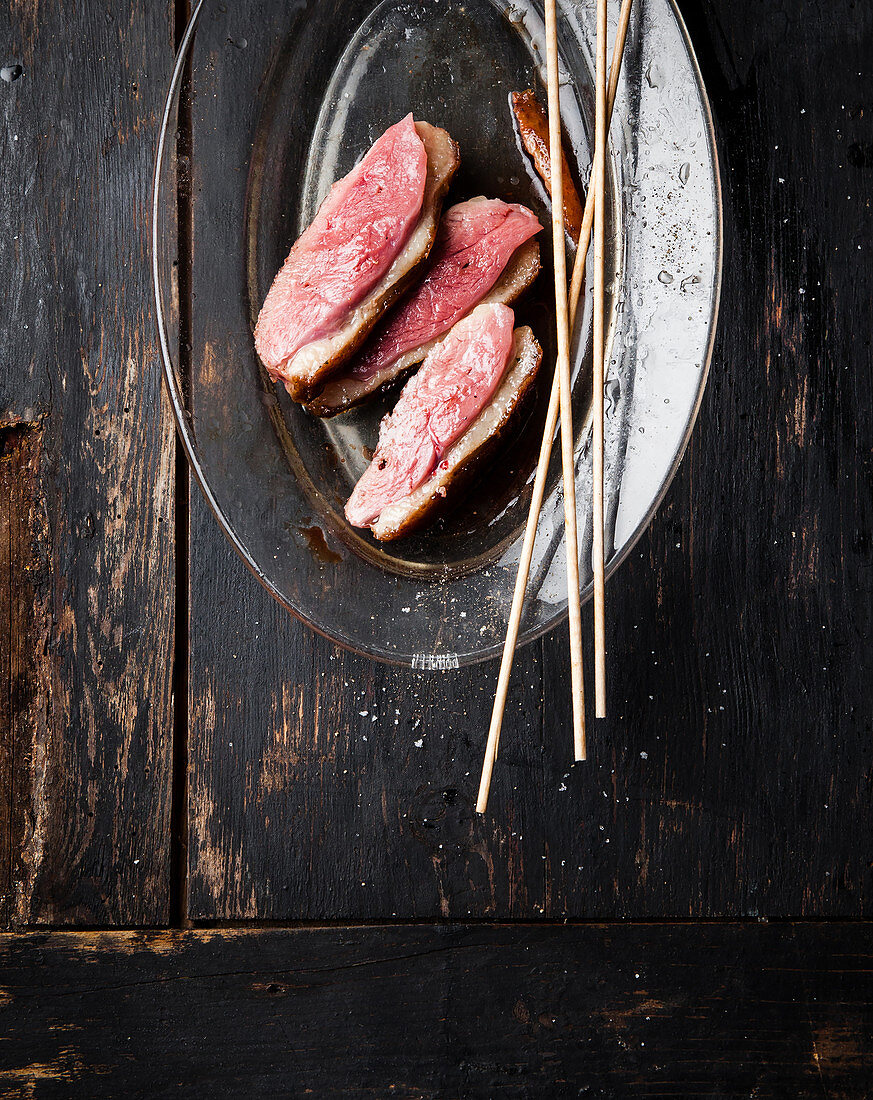 Sliced raw duck breast with wooden skewers