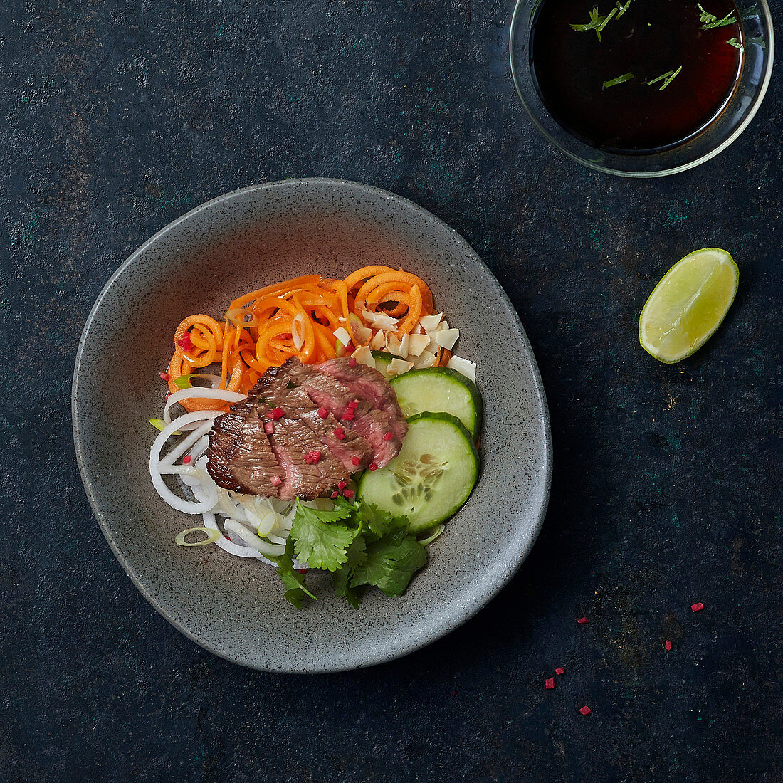 A slice of roast beef on vegetable noodles and cucumber slices