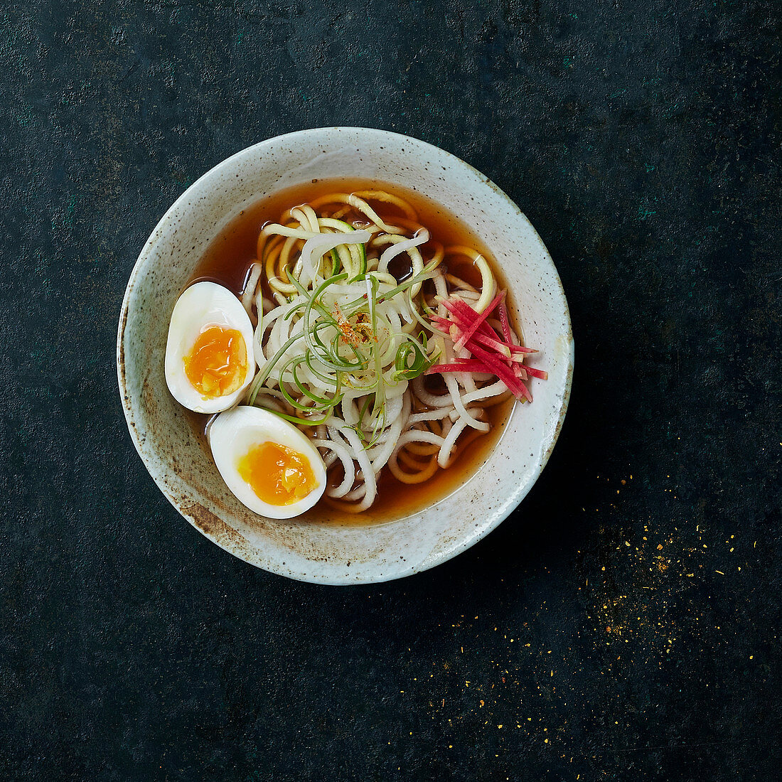 Vegetable udon noodles with black radish and courgette in broth, with soft-boiled eggs