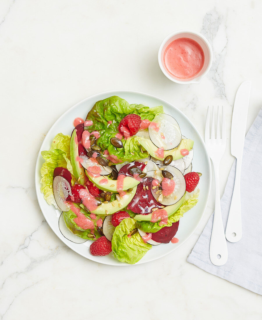 Leaf salad with raspberries, avocado, black radish, beetroot and fruit dressing