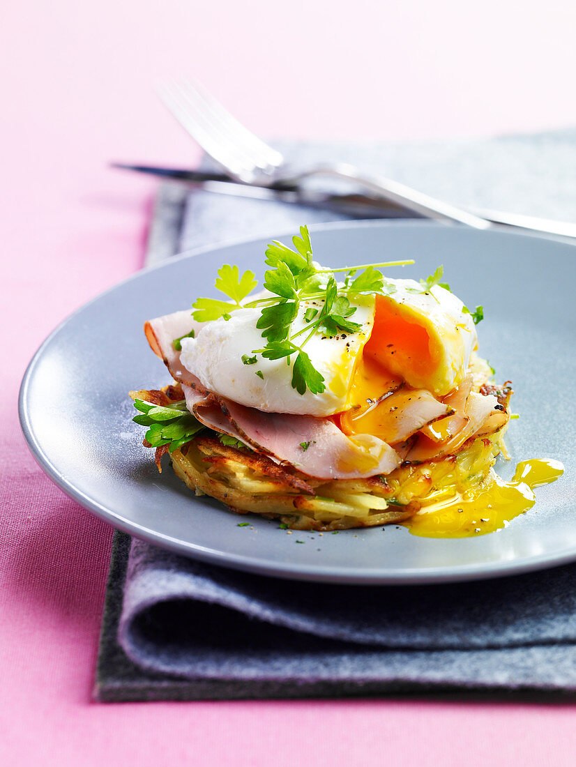 Potato hash browns with boiled ham and a poached egg