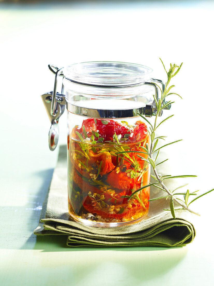 Pickled tomatoes with herbs in a glass jar