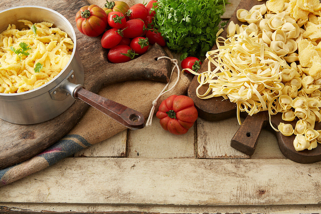 Still life with ingredients for pasta dishes with tomato and herb sauce