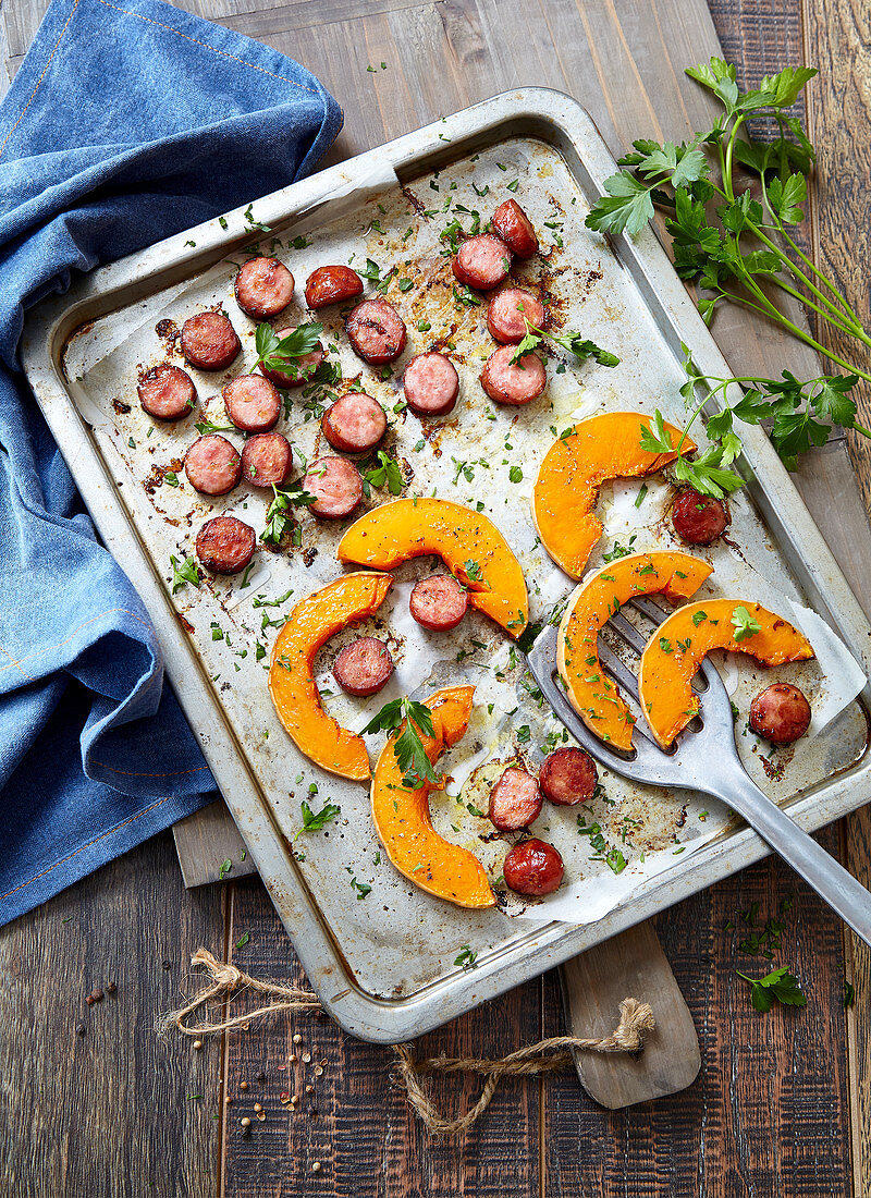 Gebratene Wurstscheiben und Kürbisspalten aus dem Ofen