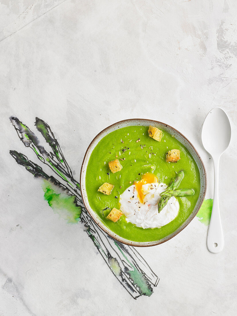 Green asparagus cream soup with poached egg and croutons