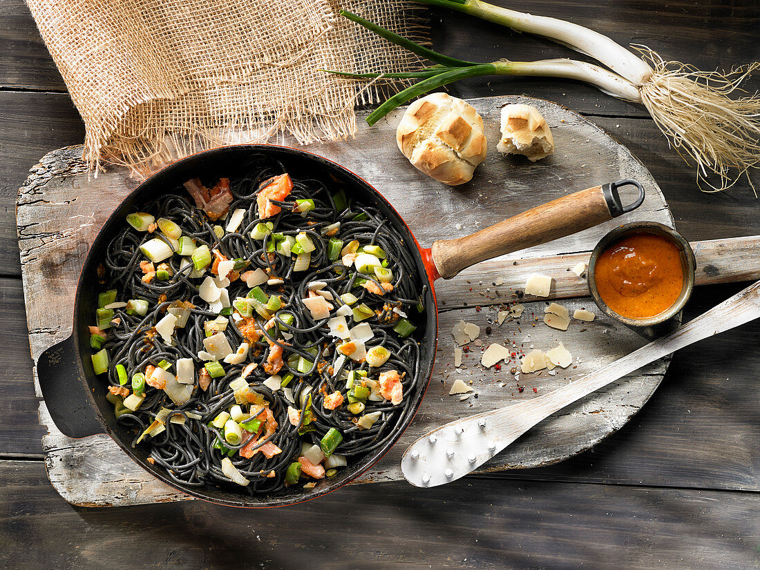 Black spaghetti with salmon, spring onions and parmesan cheese