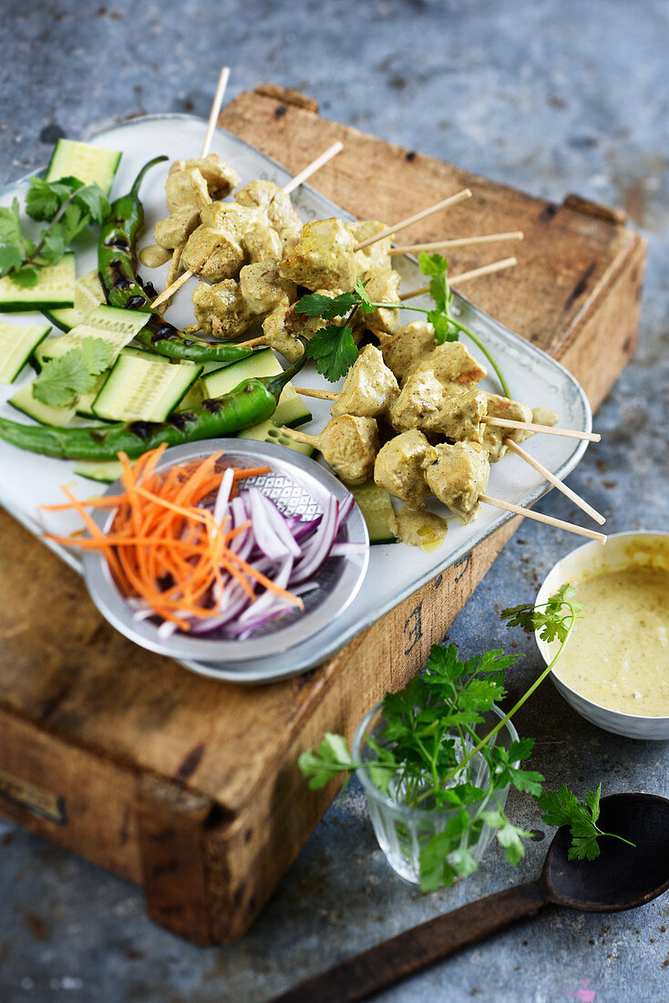 Chicken skewers with curry sauce and vegetable garnish