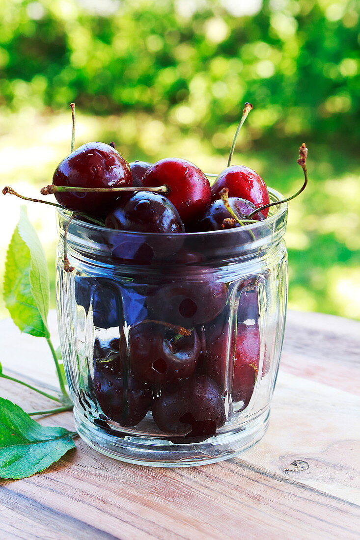 Fresh cherries in a glass on a garden table