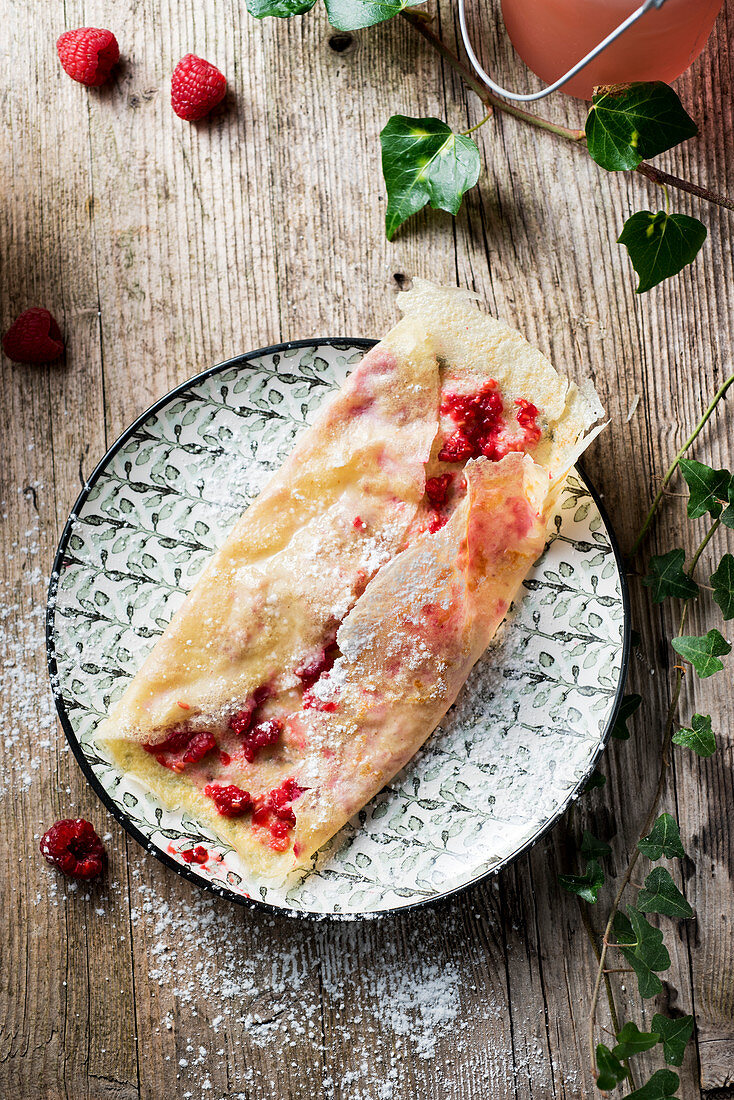 Crepes with raspberries and icing sugar