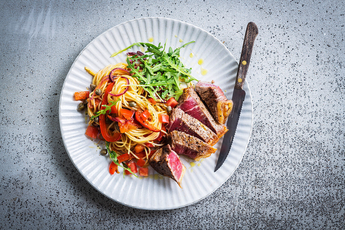 Pepper steak served with spaghetti with summer vegetables