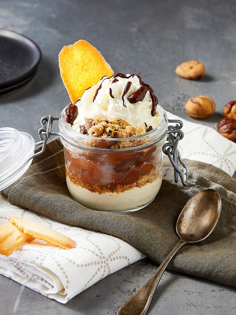 Chestnut dessert in a glass jar with biscuit crumbs and whipped cream