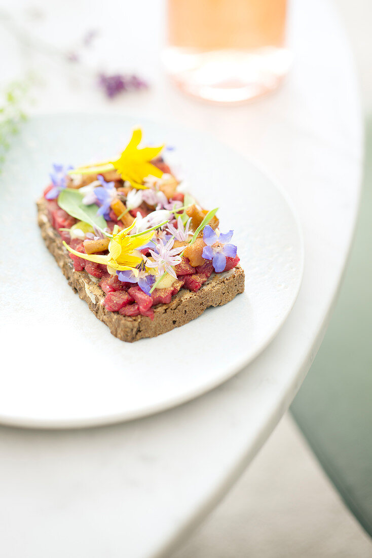 Beef tartare on bread garnished with edible flowers