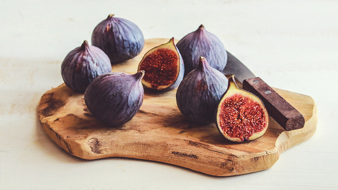 Fresh figs on a cutting board against a white background