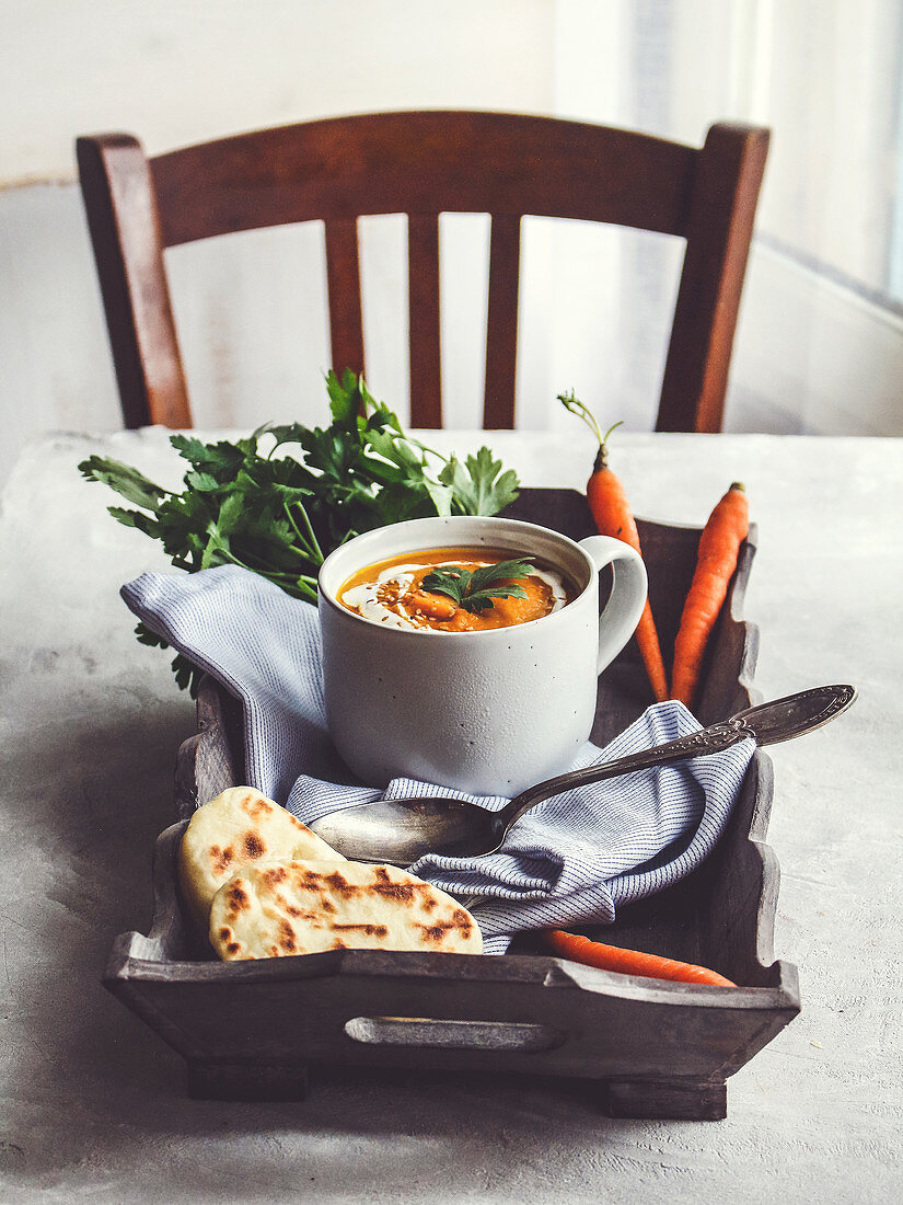 Cream of carrot soup with turmeric and cream on a wooden tray