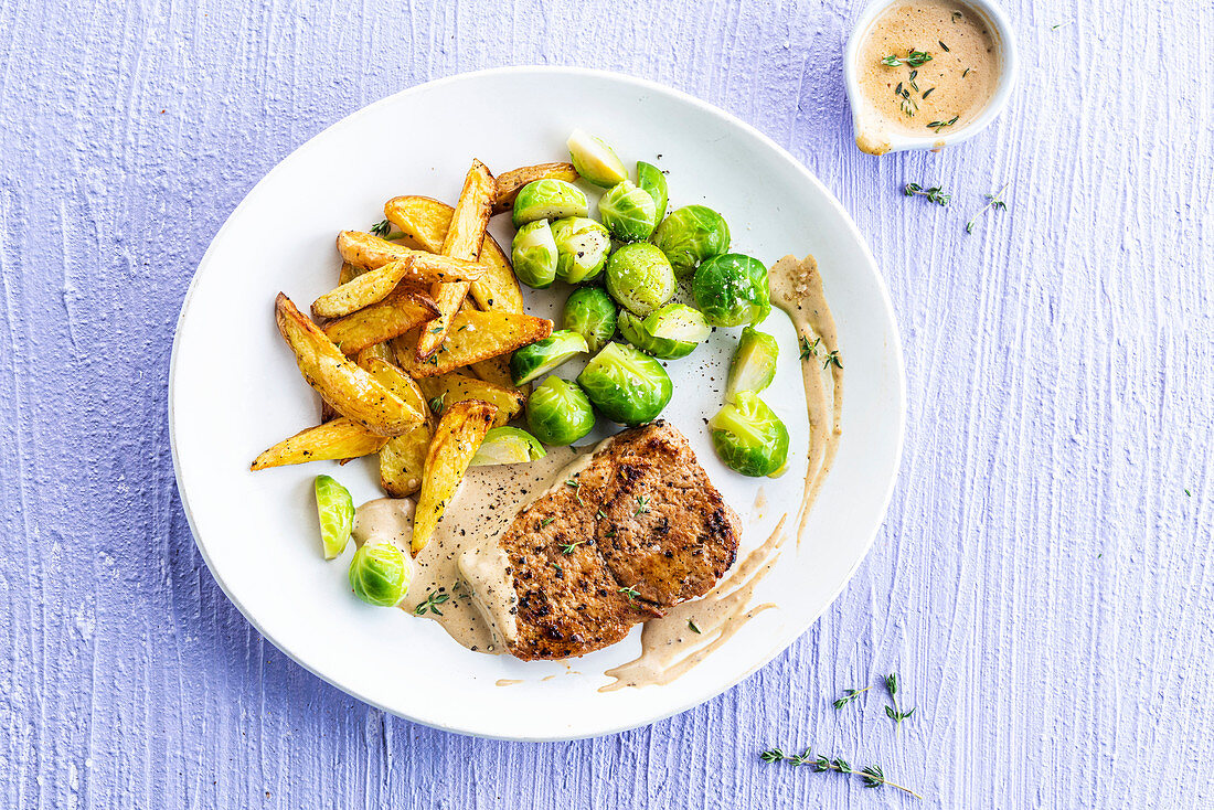 Pork steak with mustard sauce, fries and Brussels sprouts