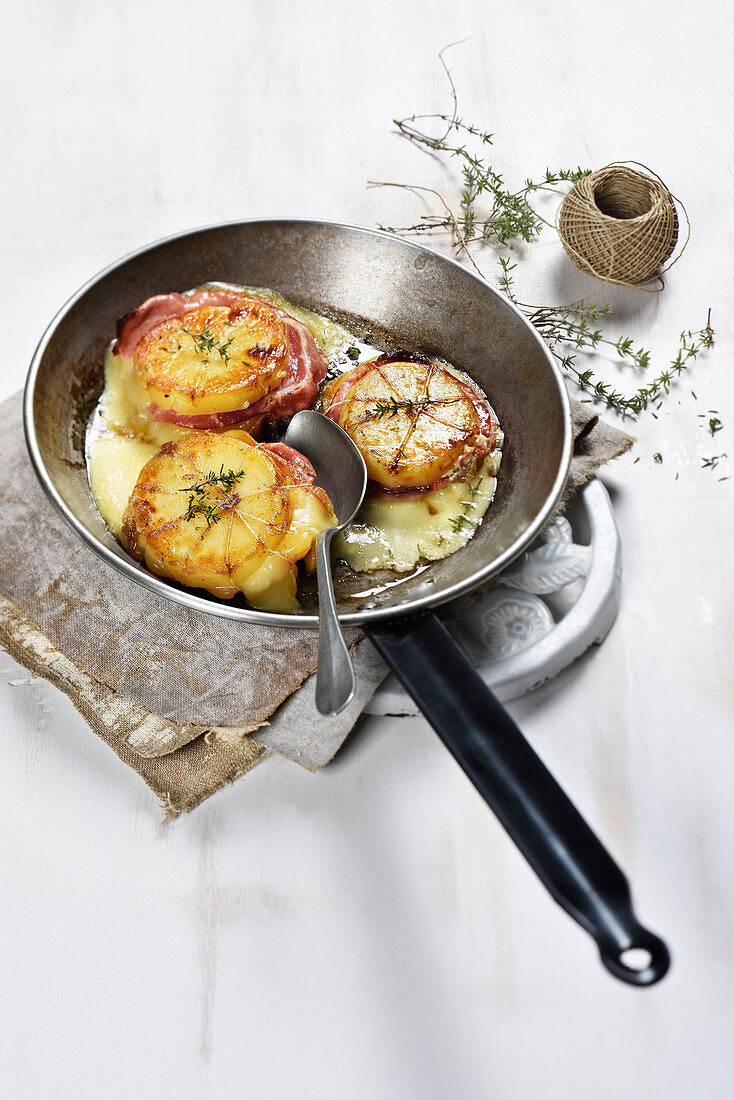Potato towers with pancetta and raclette cheese in a pan