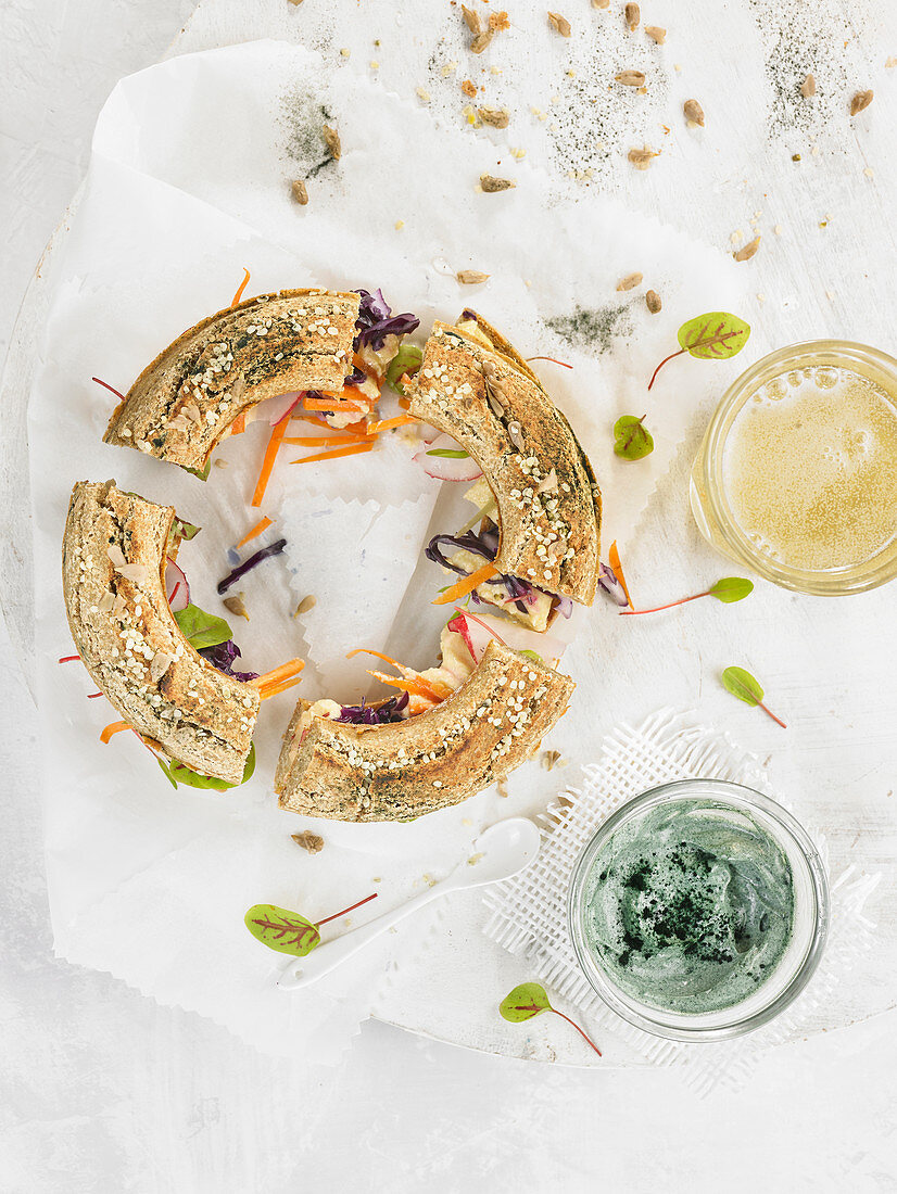 Wholegrain bread ring topped with vegetables, hummus and spirulina cream