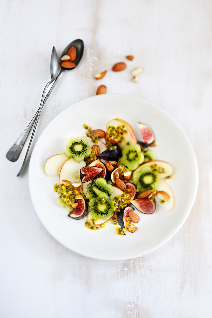 Fruit salad with apple, kiwi, fig, passion fruit and almonds