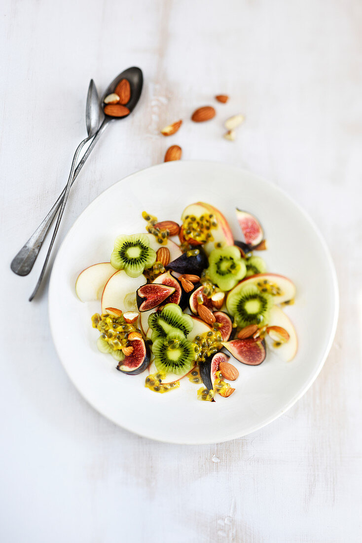 Obstsalat mit Apfel, Kiwi, Feige, Passionsfrucht und Mandeln