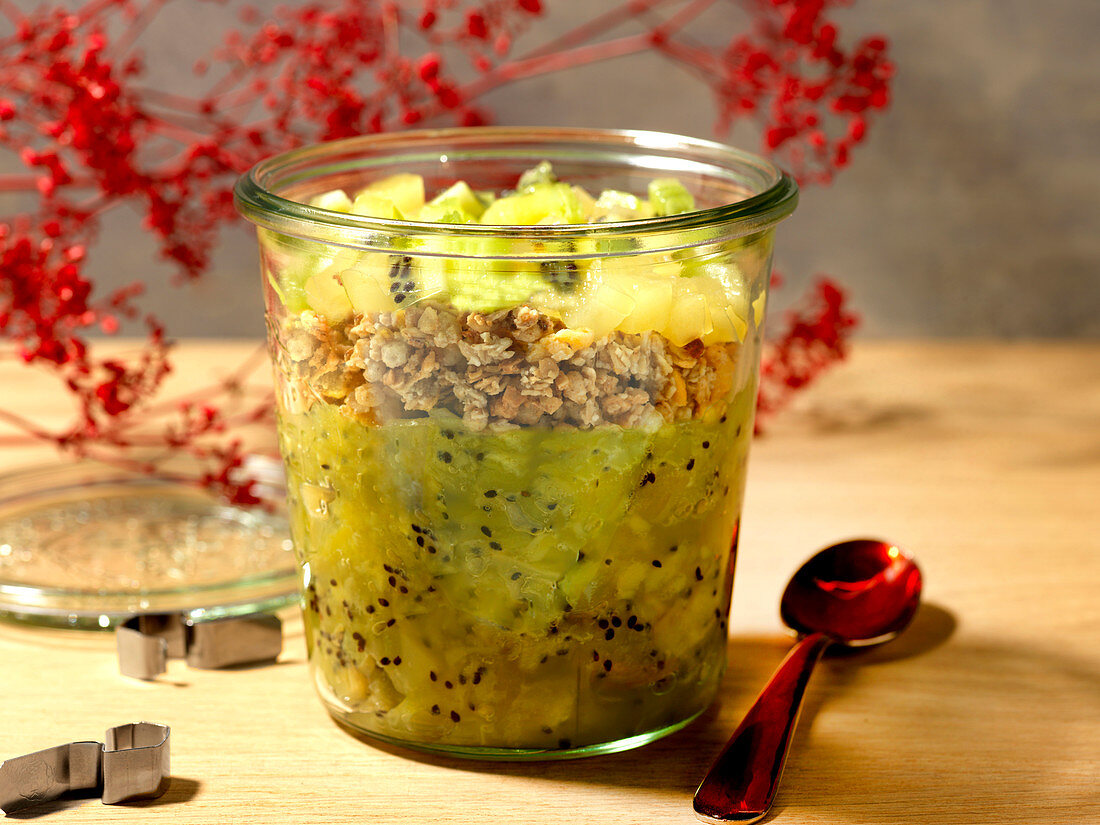 Muesli layered with applesauce and kiwi in a jar