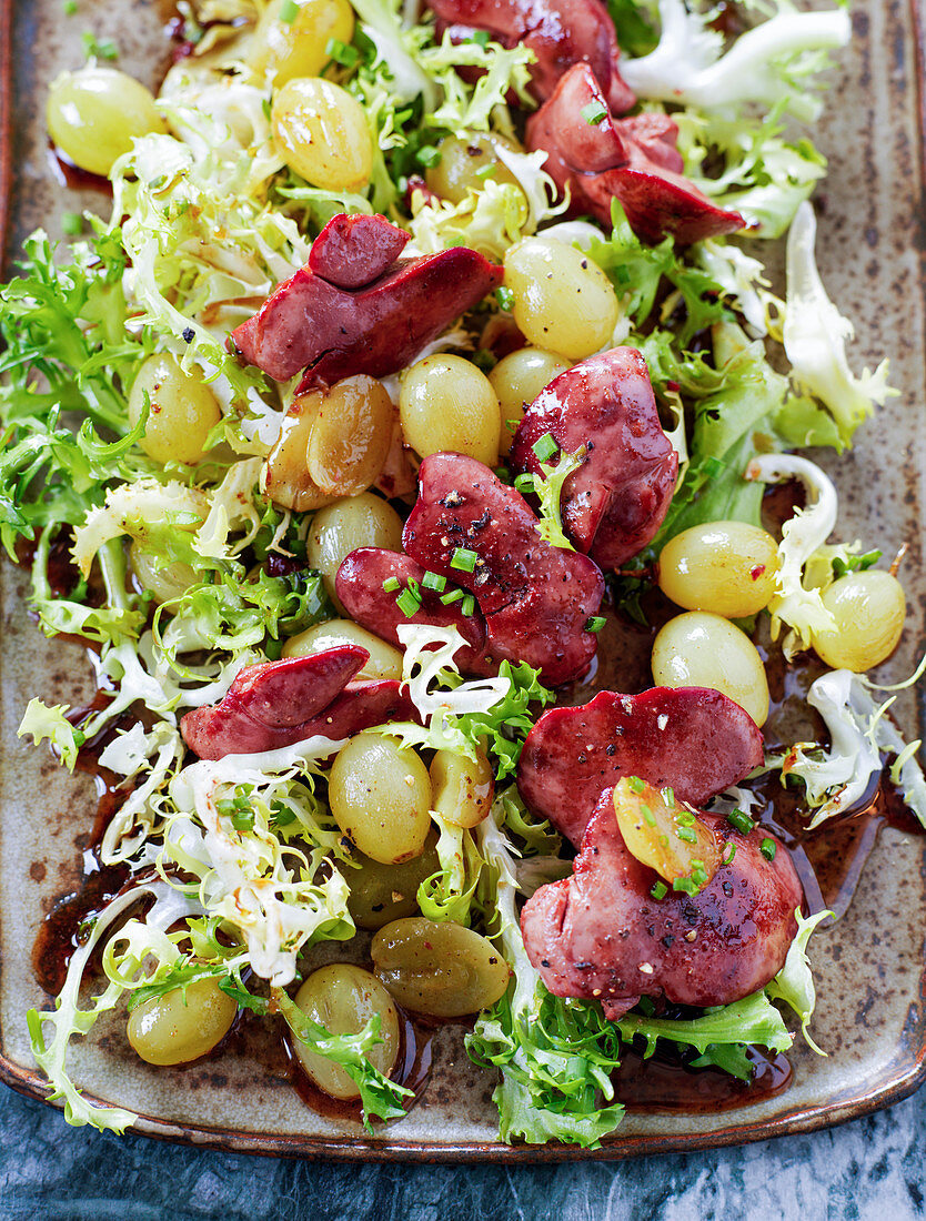 Warm liver salad with white grapes and curly lettuce