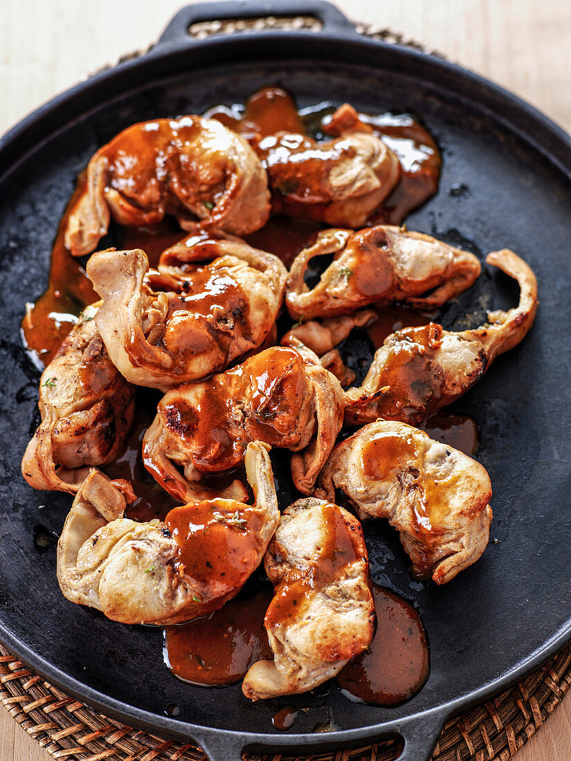 Rabbit pieces grilled on a flat grill plate with sauce