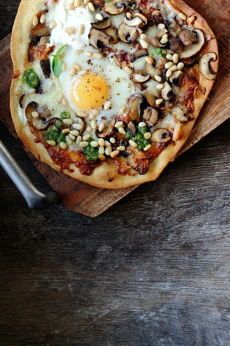 Pizza mit Pilzen, Käse, Ei und Pinienkernen