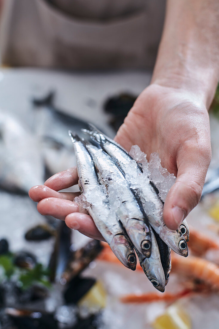 Fishmonger presenting sardines to a customer