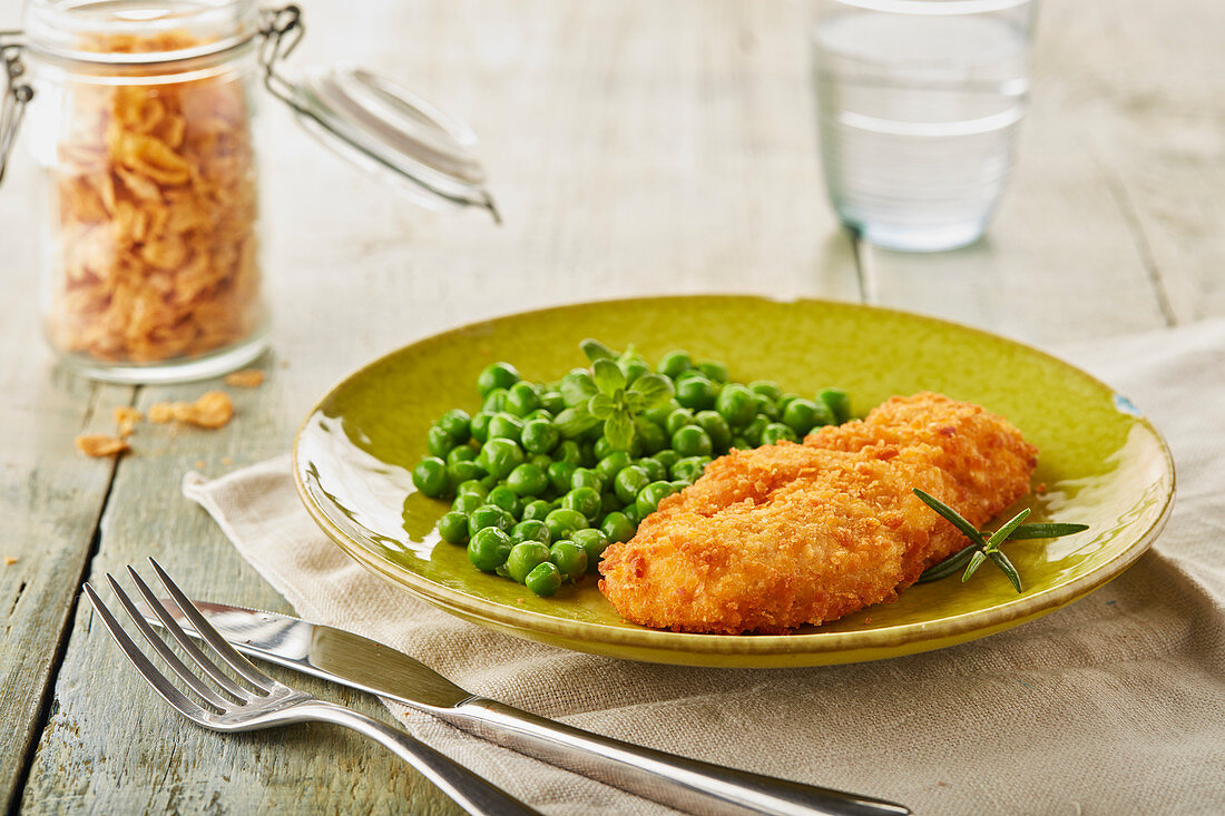 Chicken breast coated in breadcrumbs, served with peas