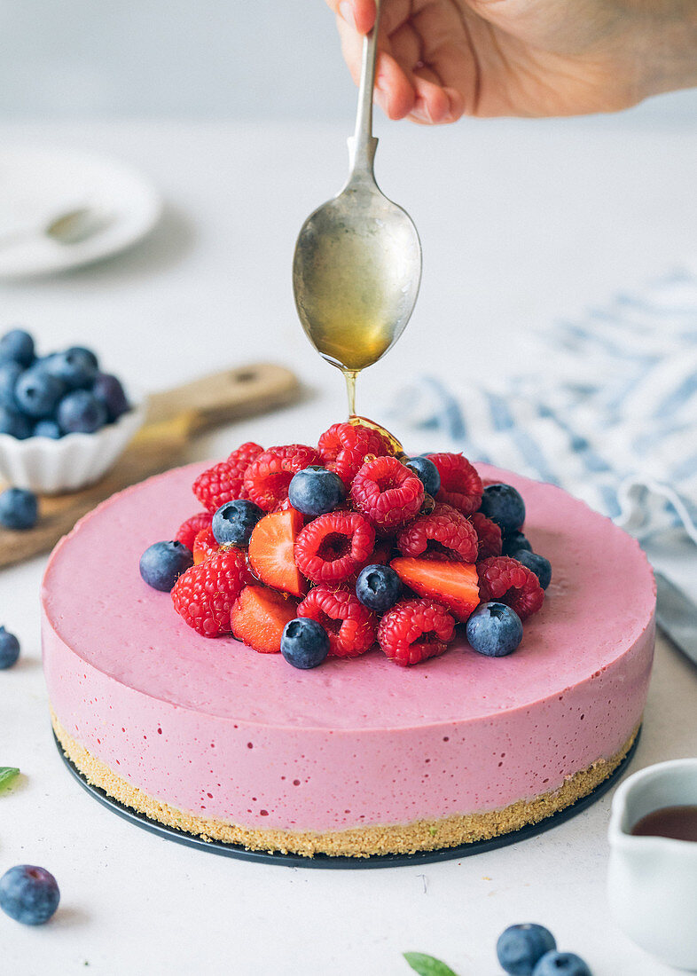 Cheese cake with red fruits and honey spoon